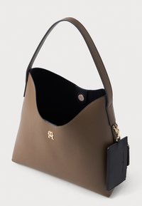 Ruda odinė rankinė su išskirtiniu kreiviu viršumi, juodu vidumi ir auksiniu logotipu. Yra nuimamas juodas kortelių laikiklis.