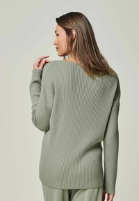 Rippstrickpullover in gedämpftem Grün, mit lockerer Passform, weiter Ausschnitt und langen Ärmeln mit strukturierten Details auf den Schultern.