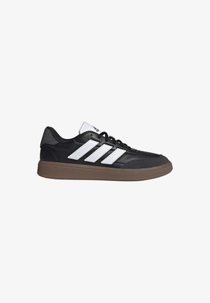 Schwarzer Sneaker mit niedrigem Schaft, weißen Adidas-Streifen, schwarzen Schnürsenkeln, weißer Zunge und brauner Gummisohle.