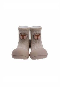 Zapatos de calcetín para toddlers en color beige con suelas de goma, que presentan un diseño de cara de oso y una corona de flores en el puño.