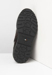 Semelle de chaussure en caoutchouc noir avec un motif de traction texturé. Comprend la marque "NeroGiardini" et les détails de la taille 37. Fini lisse.