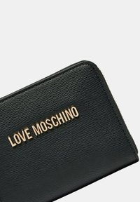 Portefeuille en cuir noir avec une surface texturée, logo doré "LOVE MOSCHINO" et fermeture éclair sur un côté.
