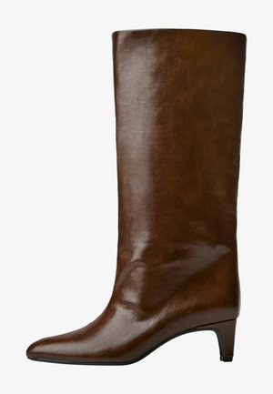 Botte en cuir marron, montant jusqu'au genou, avec un bout pointu et un talon effilé, présentant une texture lisse et un design épuré.