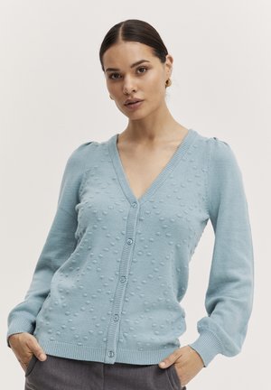 Světle modrý cardigan s výstřihem do V, tečkovanou strukturou, zapínáním na knoflíky a žebrovanými manžetami. Vyrobeno z měkkého pleteného materiálu.