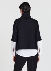 Schwarzer Strickpullover mit hohem Rippkragen und kurz gerippten Ärmeln, über einem weißen Hemd getragen. Stilvolles und strukturiertes Design.