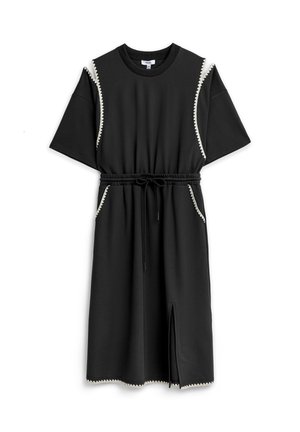 Robe noire longueur genou avec manches courtes, taille élastique avec cordon de serrage, poches latérales, fente devant, et bordure blanche en zigzag.