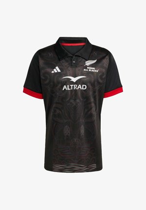 Mustapaita, jossa on monimutkaisia punaisia ja harmaita kuvioita, nappikaulus ja punaisia yksityiskohtia hihoissa. Logot näkyvät selvästi.