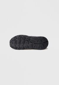 Sola exterior preta de borracha com padrões texturizados de aderência e piso elevado. Apresenta logótipo na lateral. Projetada para tração em superfícies variadas.