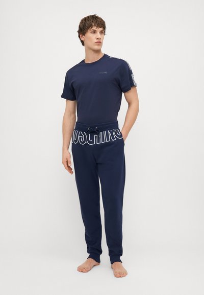 Námornícky modré bavlnené tričko s krátkymi rukávmi a logom, v kombinácii s námorníckymi joggermi s bielou potlačou loga na nohavici a elastickým pásom.