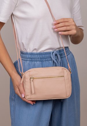 Lichtroze schoudertas gemaakt van textured leer. Bevat een voorzak met ritssluiting, goudkleurige hardware en een verstelbare schouderriem.