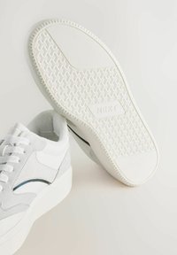 Sneakers bianchi con tomaia in suede e pelle, suola in gomma testurizzata con grip a motivo e un design semplice senza logo visibili.
