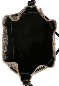 Tote-väska med en strukturerad beige utsida och svarta tyginsidan. Har en scallopformad övre kant och läderdetaljer. Öppen och rymlig inredning.