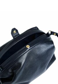 Musta nahkalaukku, jossa on teksturoitu pinta, varustettu vetoketjuläpällä ja kultaisilla yksityiskohdilla. Pyöreä muoto, sivukahva näkyvissä.