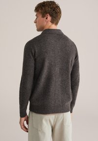 Mörkgrå stickad tröja med sjalkrage och ribbad nederkant, med en texturerad finish. Designad för en avslappnad passform, är ärmarna något figurnära.