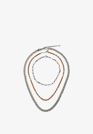 Three necklaces arranged in a circle: a silver chain, a brown beaded necklace with turquoise accents, and a small shell necklace with blue string.