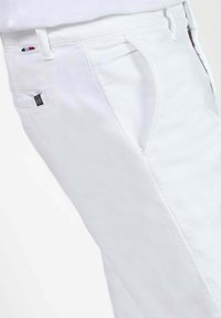 Witte katoenen broek met een slim fit, voorzien van zijzakken en een klein logo-etiket op de achterzak. Gladde textuur, minimalistisch ontwerp.