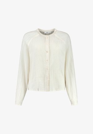 Chemise légère de couleur crème à manches longues, en tissu texturé, avec un col rond. Présente un léger détail froissé.