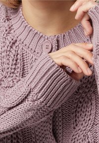 Stickad tröja i ljuslila med ett texturerat mönster, med rund hals, ribbade ärmslut och knappförsedd stängning.