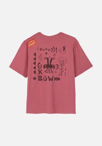 T-shirt en coton bordeaux avec un imprimé graphique noir comprenant diverses formes, des fleurs et un design avec des oiseaux stylisés dans le dos.
