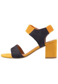 Sandaali suede-bloqi, me të sipërme ngjyrë të errët blu, akcentet elastike të verdha, dizajn të hapur për gishtat e këmbës dhe një thembër të verdhë me teksturë.