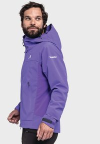 Lila wasserdichte Jacke mit Kapuze, die mit Reißverschlusstaschen, verstellbaren Manschetten und kontrastierenden Paneelen in lila Tönen ausgestattet ist.