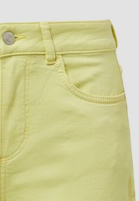 Jasnożółte dżinsy z guzikowym zapięciem, szlufkami na pasek i jedną przednią kieszenią z żółtymi detalami przeszycia.