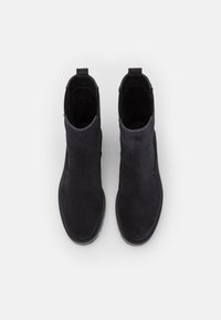 Pair of black suede ankle boots with pull tabs and rounded toes, viewed from above on a white background.
