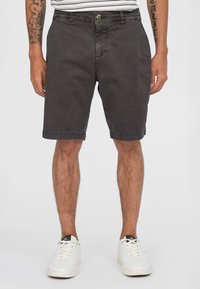 Grijze katoenen shorts met een ontspannen pasvorm, knielengte zoom, zijzakken en een knoopsluiting, gecombineerd met witte sneakers.