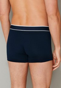 Navy blue boxer shorts made of soft fabric with a white striped waistband. The design features a fitted cut and smooth texture.