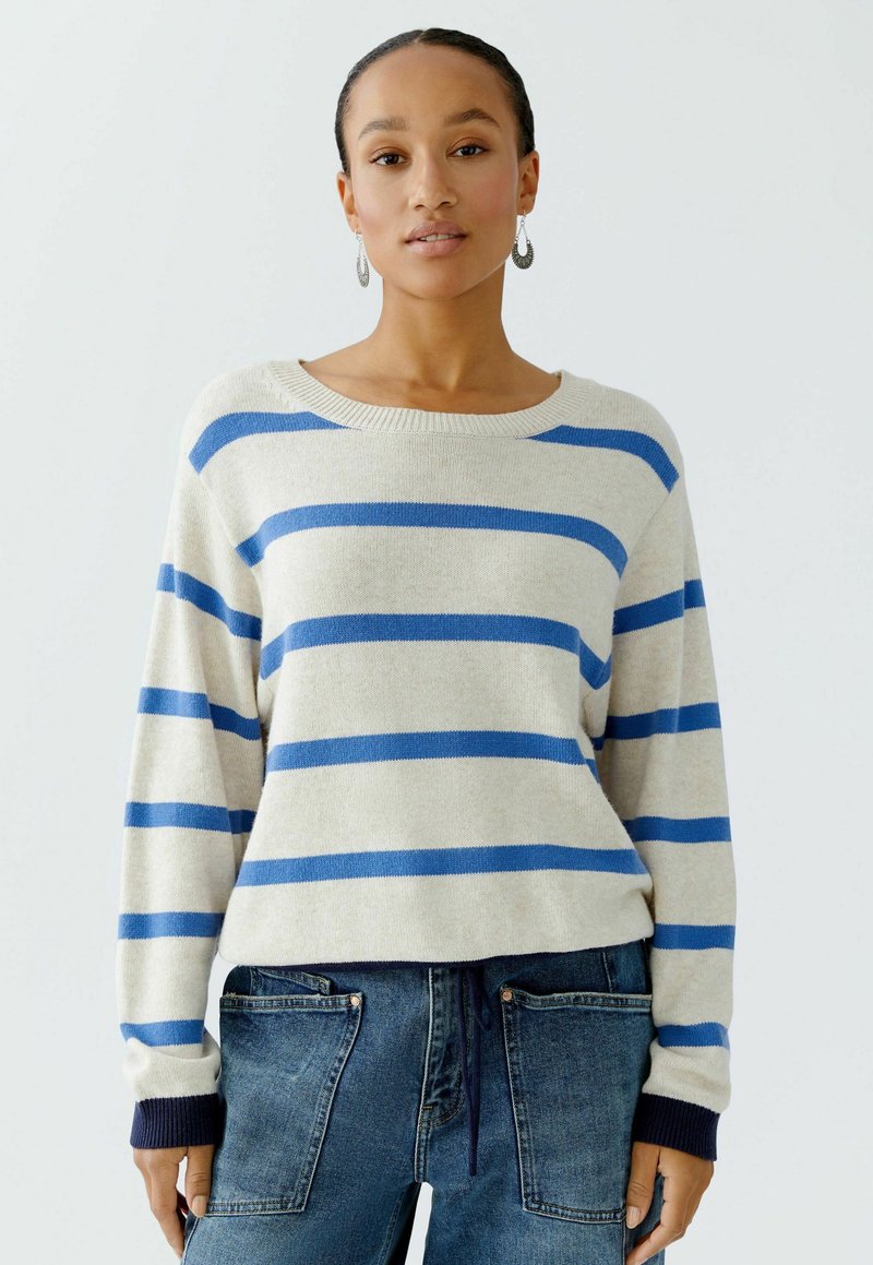 Pullover mit beigem Grund und horizontalen blauen Streifen. Verfügt über einen weiten Ausschnitt und gerippte Bündchen in Marineblau. Weiche, gestrickte Textur.