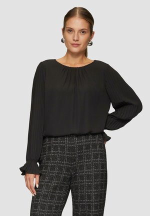 Zwarte blouse met lange mouwen, geplooide mouwen en een ronde halslijn, gecombineerd met textuur gemêleerde zwart-witte broek.