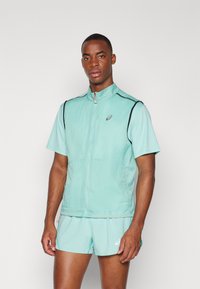 A lightweight, short-sleeved, mint green athletic jacket with a high collar, black accents, and a zip closure. Matching shorts complete the look.