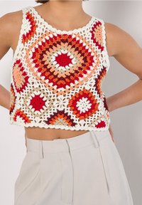 Gehaakte crop top met een cirkelmotief in rood, oranje, beige en wit; open gebreid ontwerp met een golvende zoom.