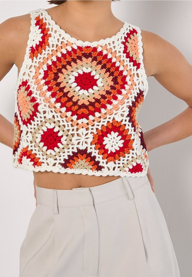 Gehaakte crop top met een cirkelmotief in rood, oranje, beige en wit; open gebreid ontwerp met een golvende zoom.
