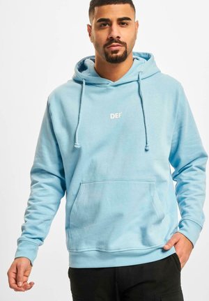 Light blue hooded sweatshirt in soft fabric with front pocket, drawstrings, and white "DEF" logo on the chest. Adjustable fit, casual design.