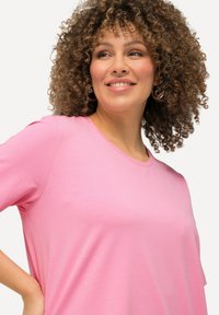 T-shirt rosa a maniche corte realizzato in tessuto morbido con una vestibilità rilassata, caratterizzato da un collo rotondo e una texture liscia.