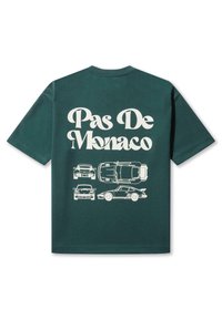 Zöld pamut póló, fehér grafikai nyomattal, autókkal és a "Pas De Monaco" felirattal a hátoldalon. Rövid ujjú és kerek nyakkivágású dizájn.