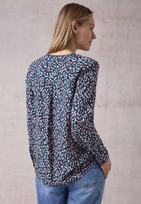 Blusa a maniche lunghe con un motivo astratto multicolore, dal taglio rilassato e in tessuto morbido. La parte posteriore presenta un dettaglio a yoke e delle pieghe.