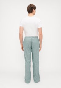 Triibulised püksid, millel on lõdva istuvuse, elastne vöökoht ja helesinine värv koos valgete vertikaalsete triipudega. Lame ees, ei ole nähtavaid taskuid.