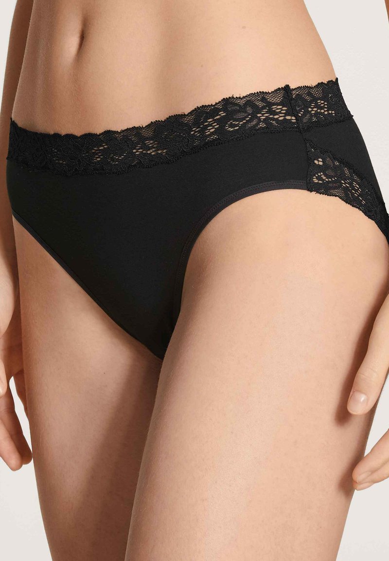 Schwarze Unterwäsche mit einem Spitzenbund und floralen Mustern, aus weichem Stoff und mit glatter Oberfläche; mittelhoher Schnitt mit einem dezenten Schnitt.
