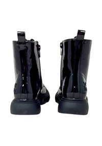 Stivaletti alla caviglia in pelle verniciata nera con una finitura lucida, caratterizzati da una suola robusta, chiusura con zip e linguetta sul retro.