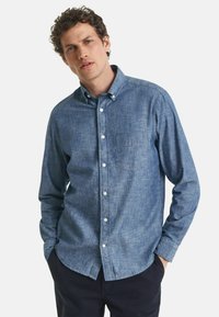 Lys blå button-up skjorte i struktureret stof, med en brystlomme og kravehals, lange ærmer og knapmanchetter.