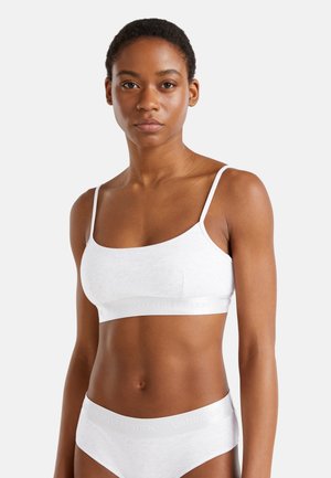 White cotton bralette with thin straps, featuring a rounded neckline and elastic band. Simple design with minimal detailing and a soft texture.