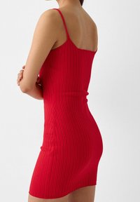 Czerwona mini sukienka z prążkowanej tkaniny, z cienkimi ramiączkami; dopasowany krój podkreśla sylwetkę; teksturowany materiał z pionowymi paskami. Prosty design.