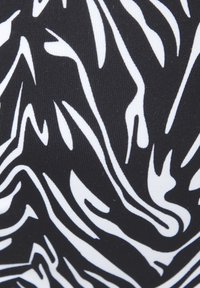Zwarte stof met een wit abstract gestreept patroon, met een getextureerd ribbeloppervlak en variërende lijndiktes voor visuele interesse.