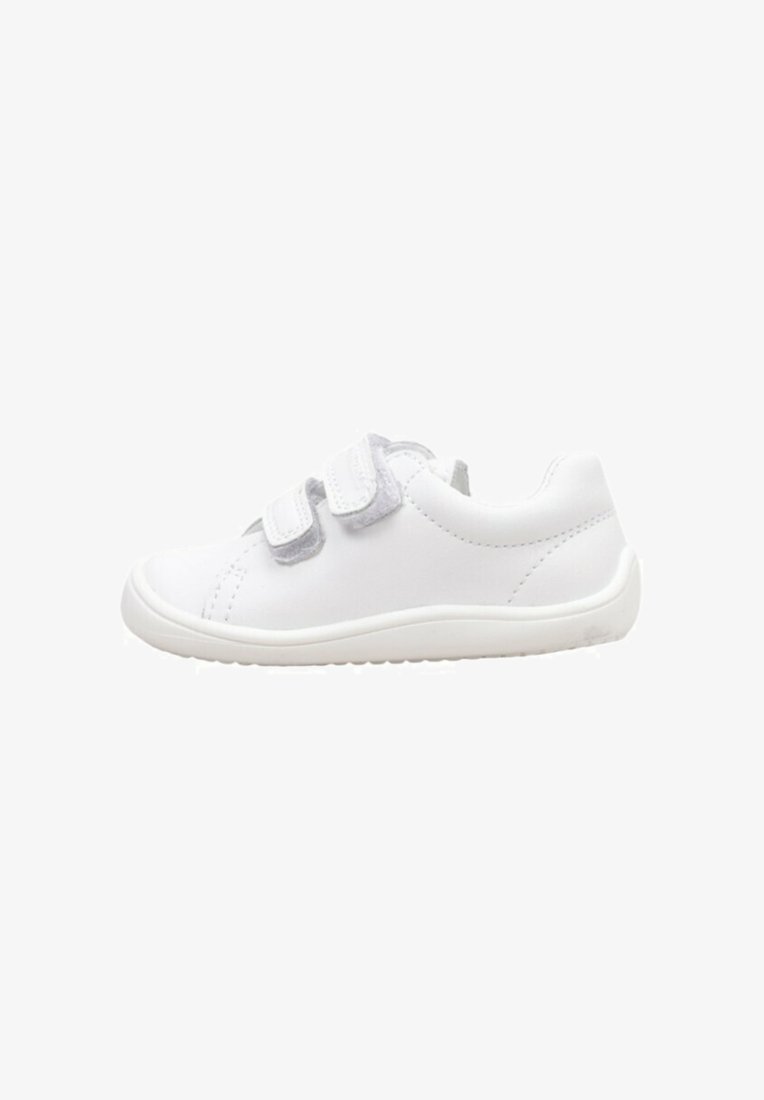 Baskets blanches en matériau synthétique lisse avec une semelle plate, dotées de deux bandes Velcro grises et de coutures décoratives.