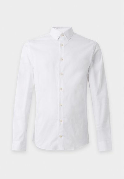 Camicia bianca a maniche lunghe con colletto classico e bottoni beige sul davanti, stesa su uno sfondo chiaro.