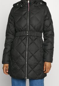 Black quilted puffer coat with a zip front, cinched waist, and hood. Features diagonal stitching and side pockets. Fabric appears smooth and glossy.