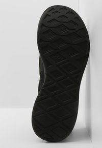 Černá gumová podešev boty s texturovaným diamantovým vzorem, který má hluboké drážky pro trakci a stabilitu.