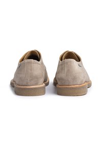 Chaussures en daim beige avec des talons ronds, doublées en cuir et semelles en caoutchouc. Présentent des détails cousus et un petit accent métallique.